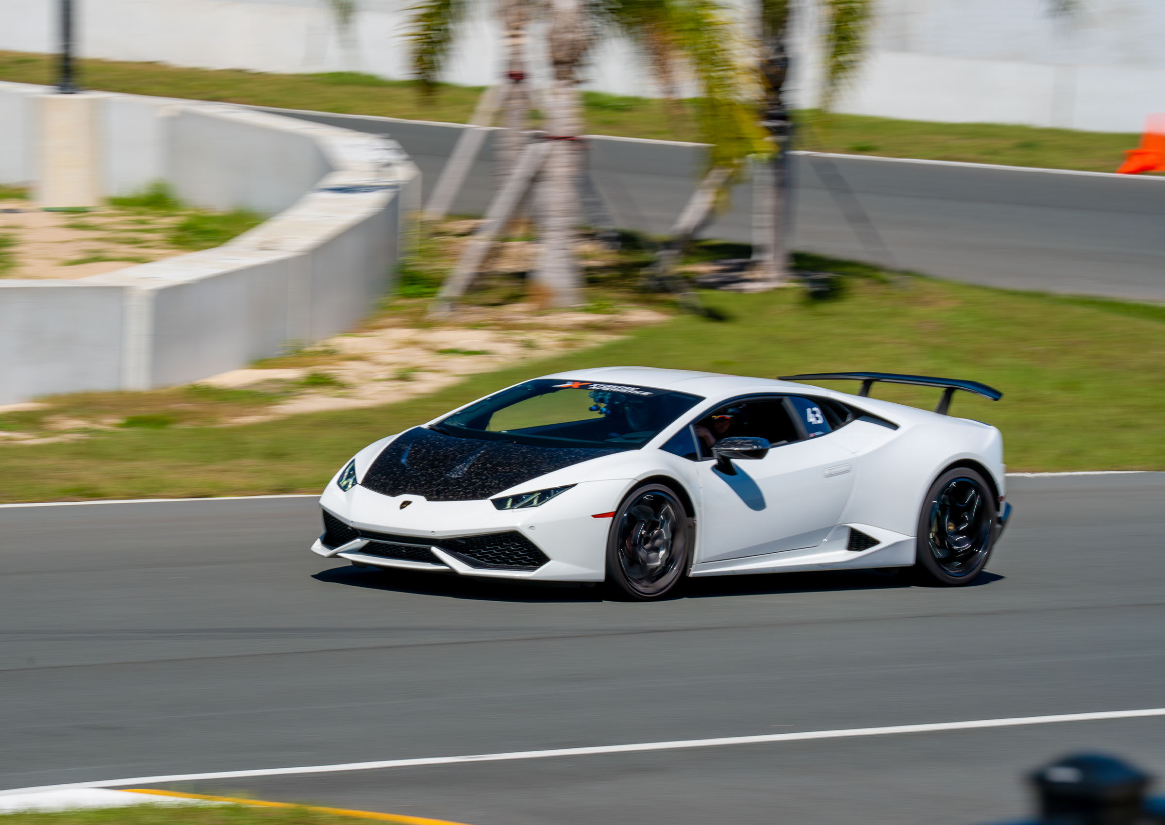 A white Lamborghini Huracán driving on track with Xtreme Xperience